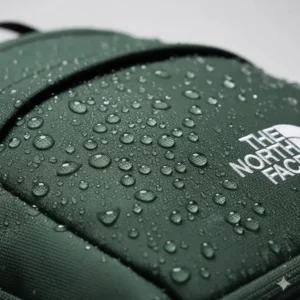 Water droplets beading on the surface of a water-resistant dark green north face backpack.