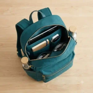 An overhead view of an open teal backpack showing organized internal pockets filled with a tablet and notebook.