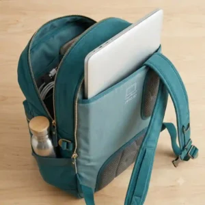 A side angle view showing a 15-inch laptop sliding smoothly into the dedicated padded compartment of a teal backpack.